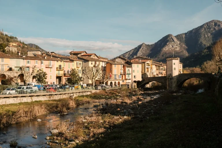 Façade urbaine de Sospel mise en valeur par ses façades colorées, ses toits en tuiles, la traversée du vieux pont et l'horizon du Mont Diaurus.